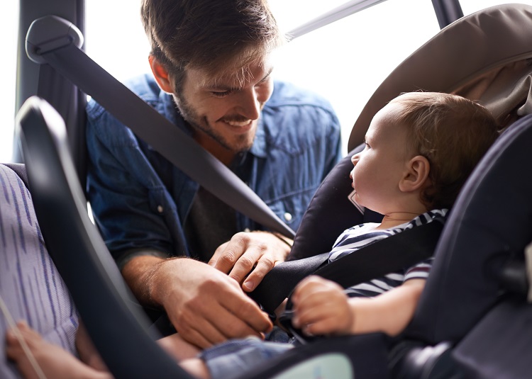 Dad strapping baby into carseat